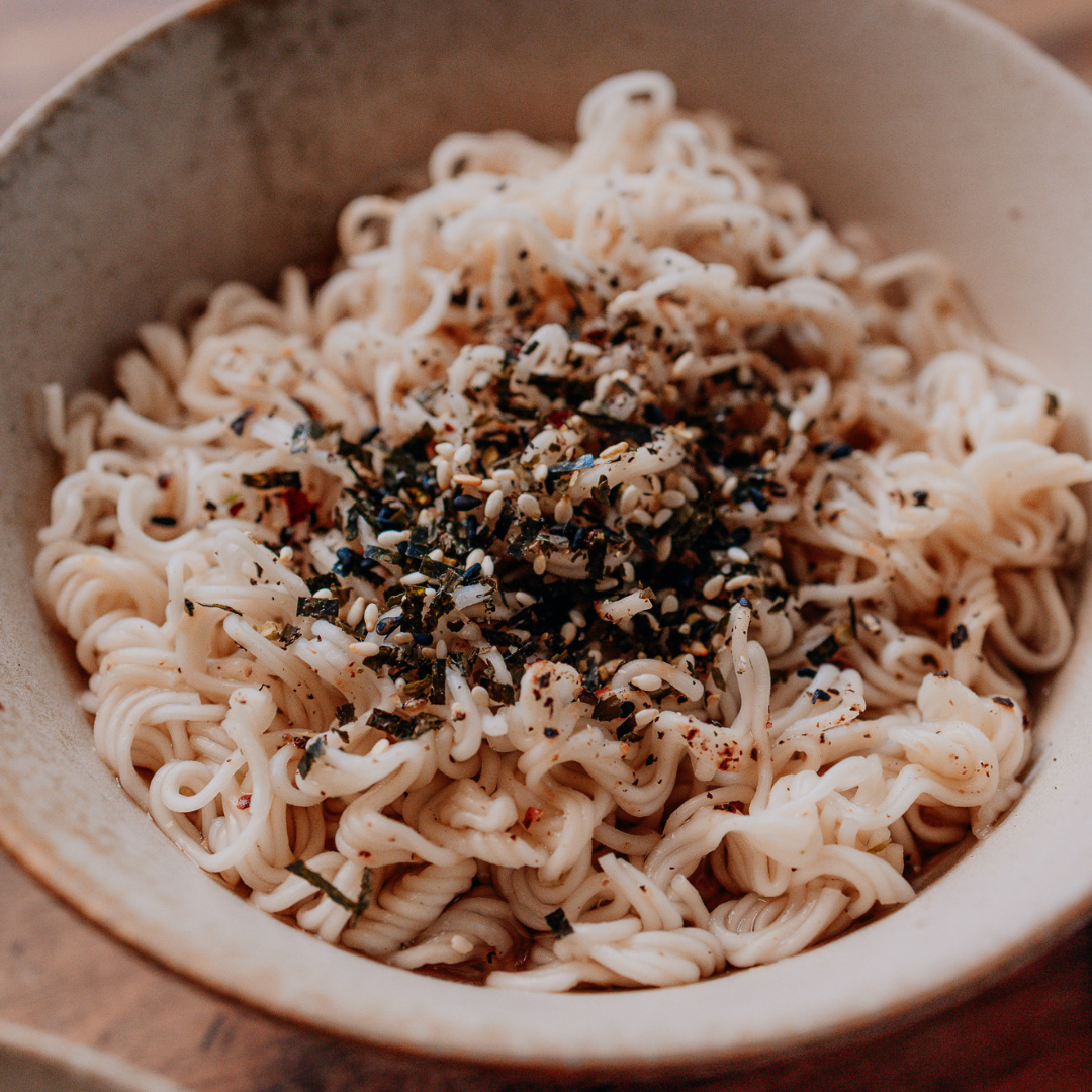 Noodles with seasoning in a bowl on a wooden surface